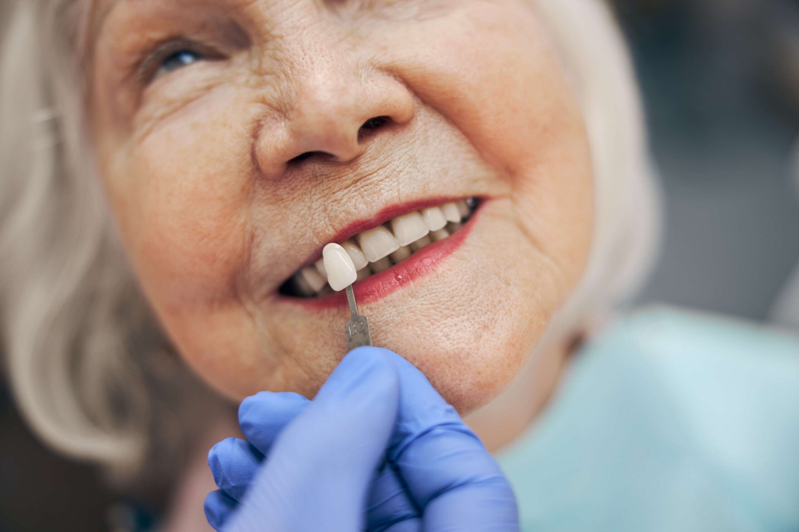 Dentist matching a tooth shade for a senior patient's smile.